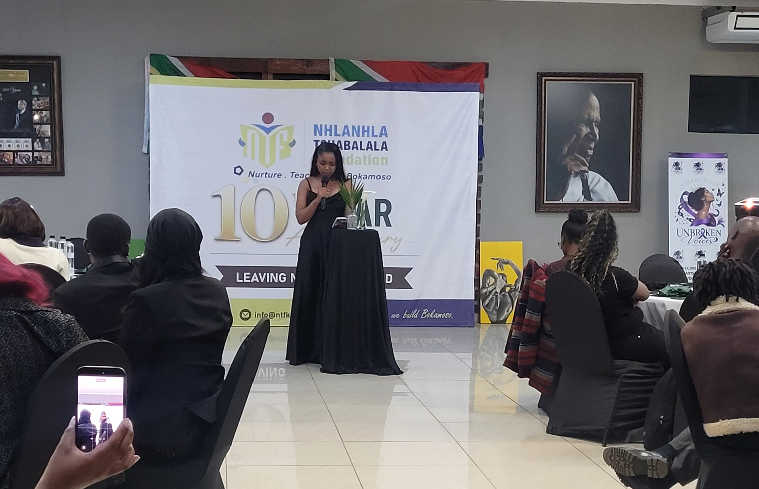 Woman speaking at a community event in front of an anniversary banner