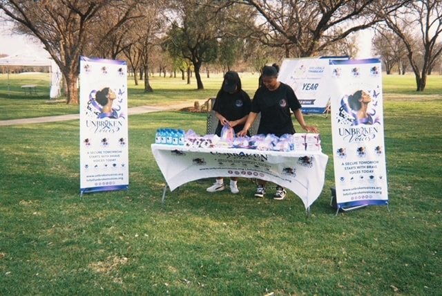 Unbroken Voices team sharing support materials at an outdoor community outreach table